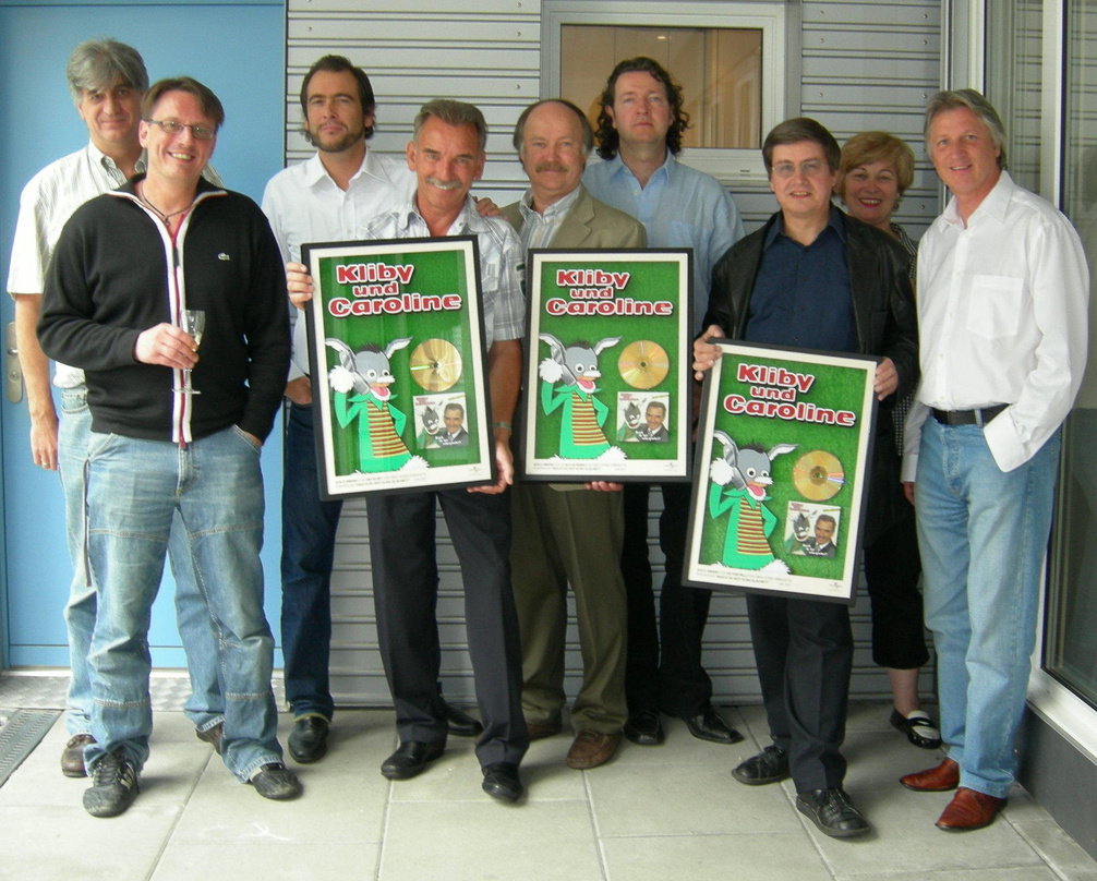 Präsentieren Gold: Bauchredner Urs Kliby (4. v. l.) und das Universal-Team||Freuen sich über Gold-Auszeichnung (v. l.): Reinhold Diermeier, Hank Merk und Ivo Sacchi (alle Universal Music S...