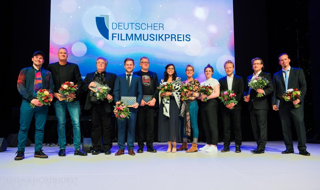 2e657c8892025d055b4092ce5cd8c284e28dab7ac2edf0183a3f8188a6112714 Die Gewinner des Deutschen Filmmusikpreises (von links): Steffen Wick, John Ottman, Enjott Schneider, David Reichelt, Michael Beckmann, Tamara Olorga, Anja Krabbe, Anna Kühlein, Simon Dete...