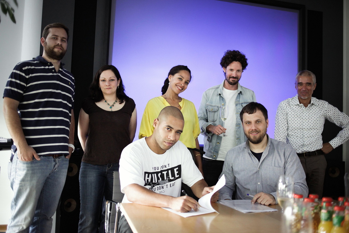 Bei der Vertragsunterzeichnung: (vorn) Megaloh (l.) und Götz Gottschalk sowie (hinten, v.l.n.r.) Chris Behrens, Sherin Kürten, Joy Denalane, Max Herre und Willy Ehmann
