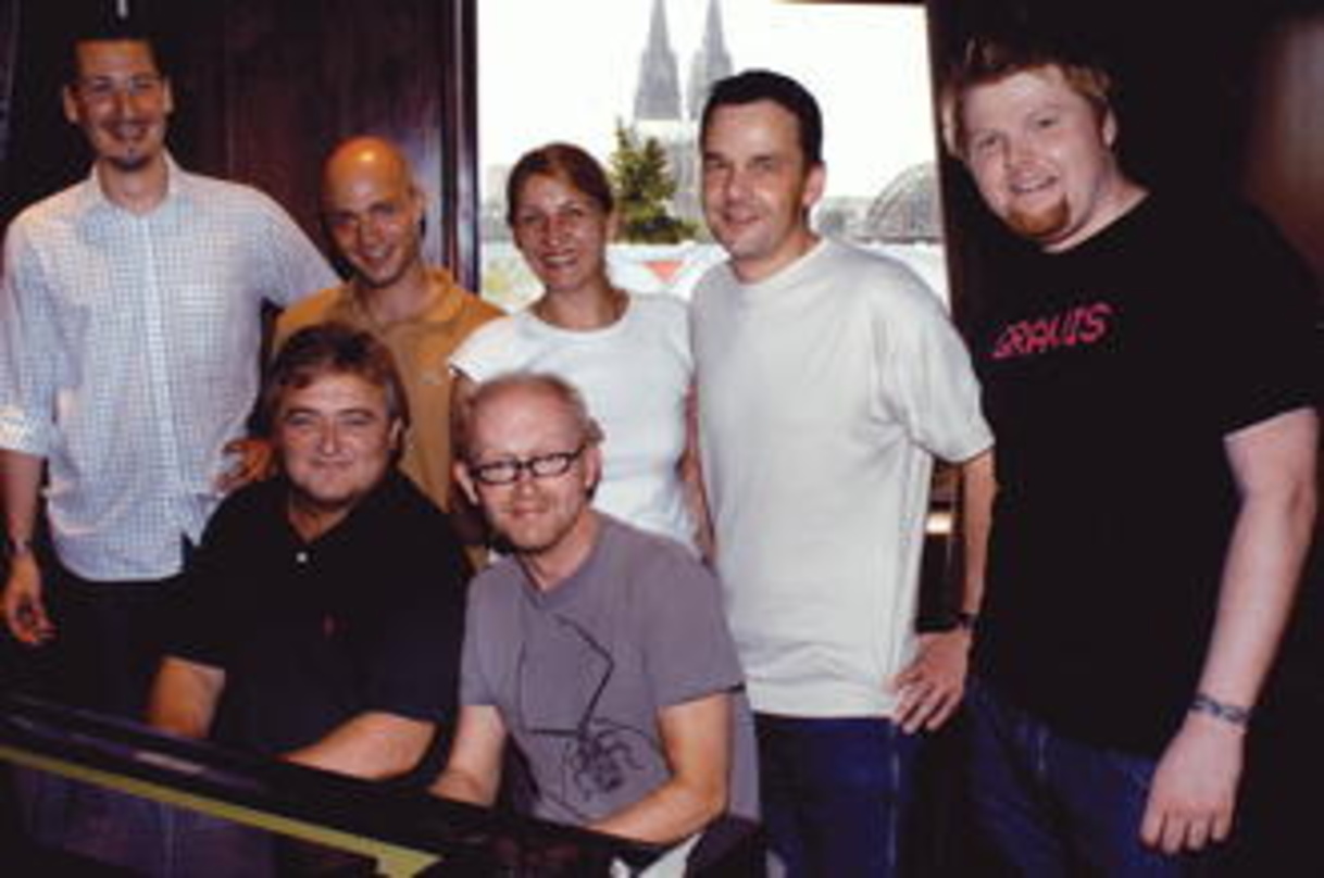 Besiegelten lange Zusammenarbeit am Klavier: Falk (r.) und Weller. Dahinter freuen sich (v.l.n.r.) Patrick Jöst (Manager Song Marketing/Sync Licensing), {mlbipers.11495.Patrick Strauch|U|T...