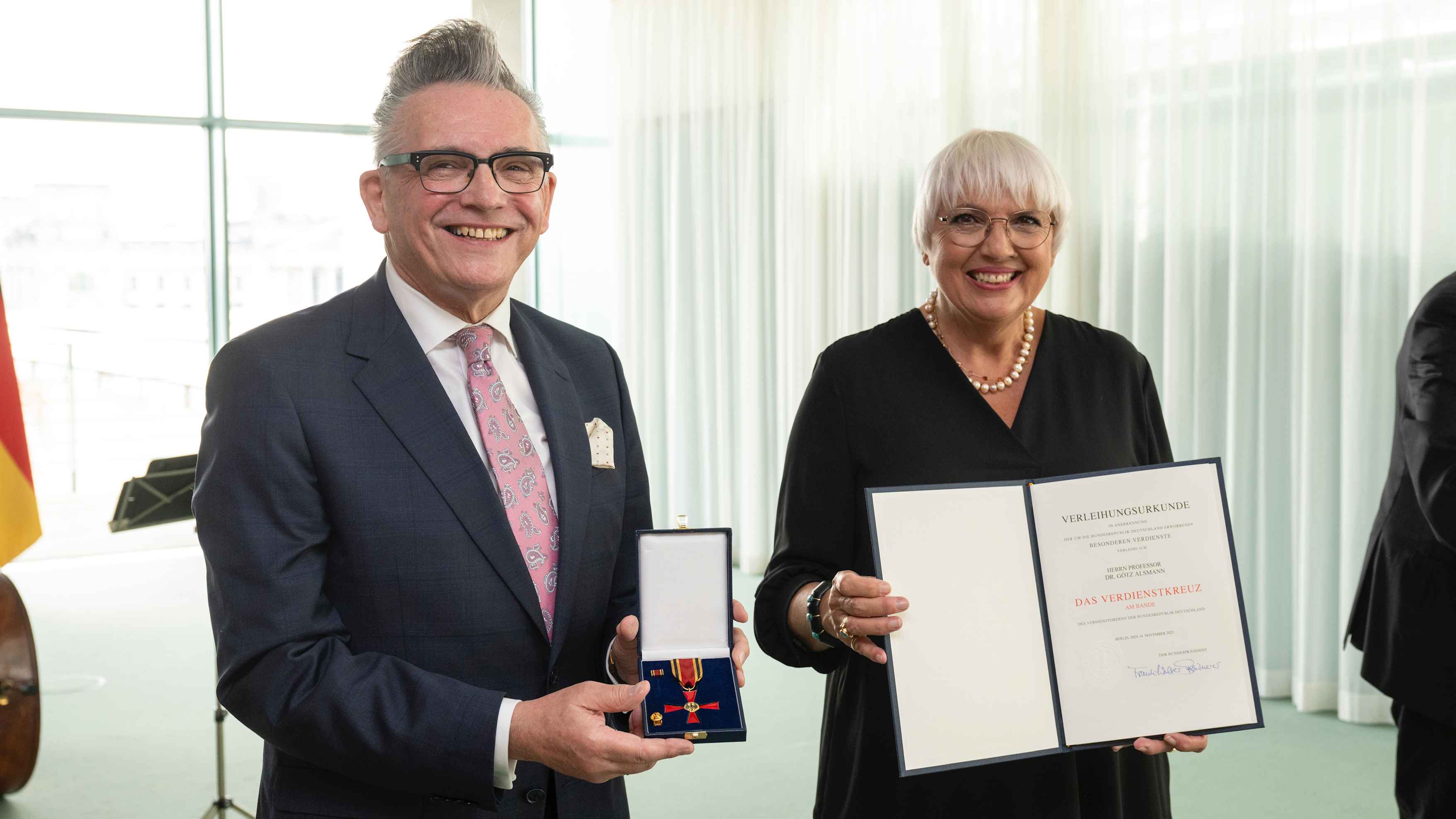 Halten grinsend den Orden und die Urkunde (von links): Götz Alsmann und Claudia Roth.
