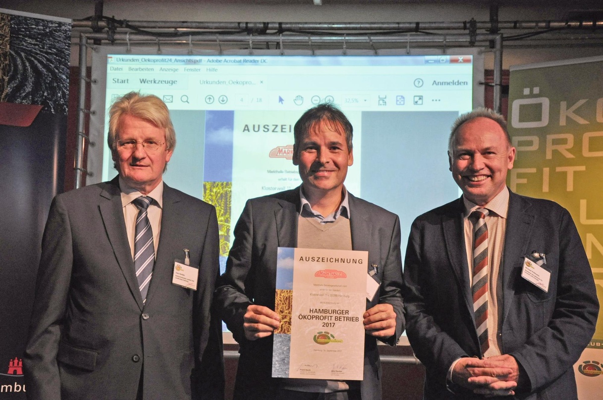 Freut sich über das Zertifikat:: Markhtallen-Geschäftsführer Mike Keller bei der Verleihung mit den Überbringern Uwe Harden (links) und Michael Pollmann