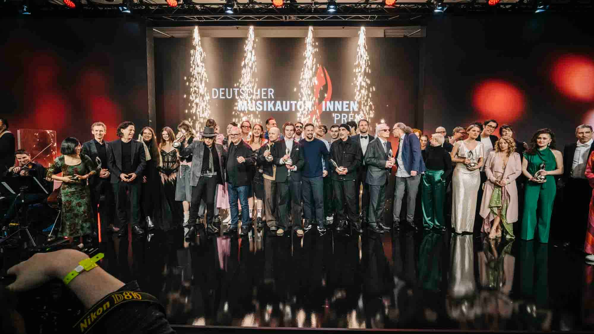 Auf der Bühne des The Ritz Carlton in Berlin: die Sieger:innen, Nominees und Laudator:innen beim Deutschen Musikautor:innenpreis 2026.