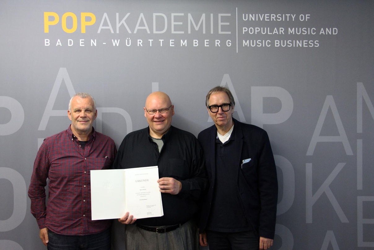 Drei Professoren: Die Popakademie-Geschäftsführer Hubert Wandjo (links) und Udo Dahmen (rechts) nehmen Frank Itt bei der Übergabe der Ernennungsurkunde in die Mitte