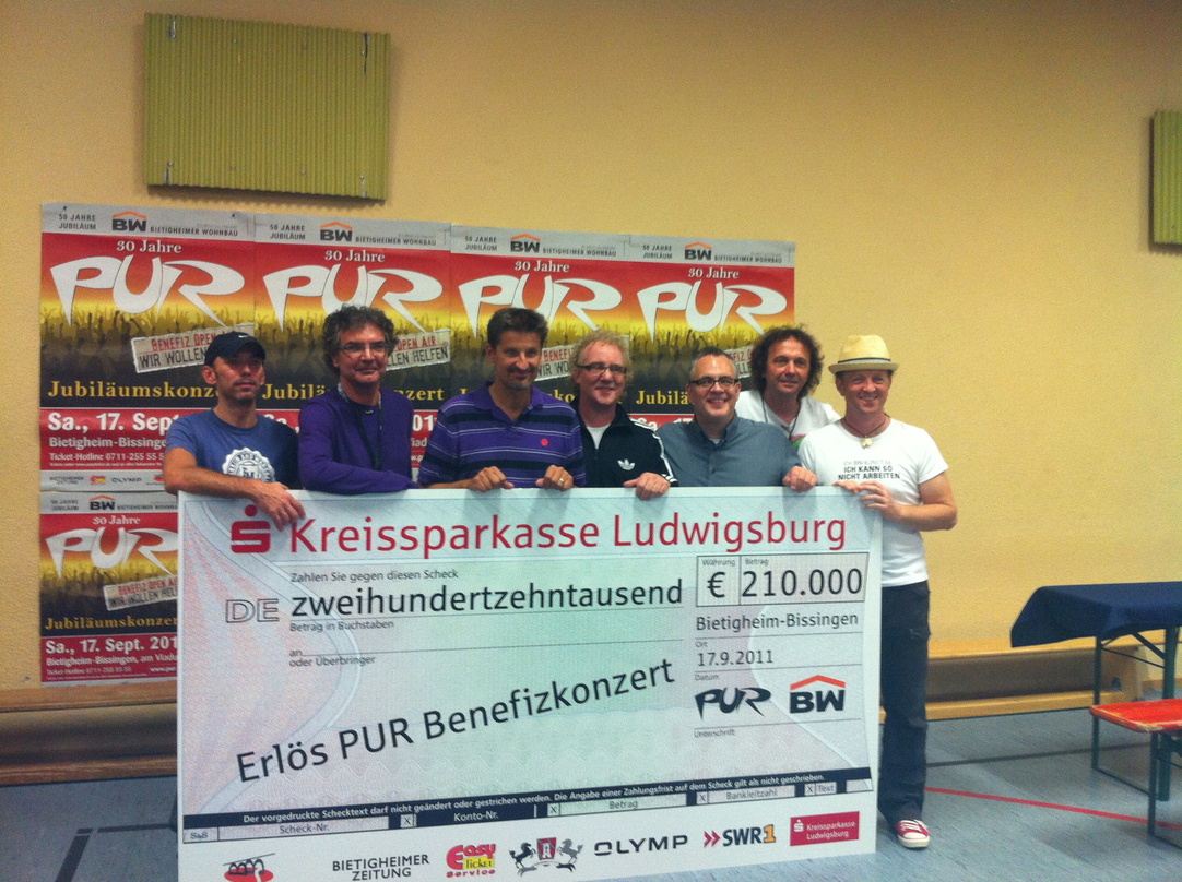 Helfen Bedürftigen mit großem Scheck (v.l.n.r.): die Pur-Musiker Martin Ansel, Ingo Reidl, Hartmut Engler, Cherry Gehring, Martin Stoeck, Rudi Buttas und Joe Crawford