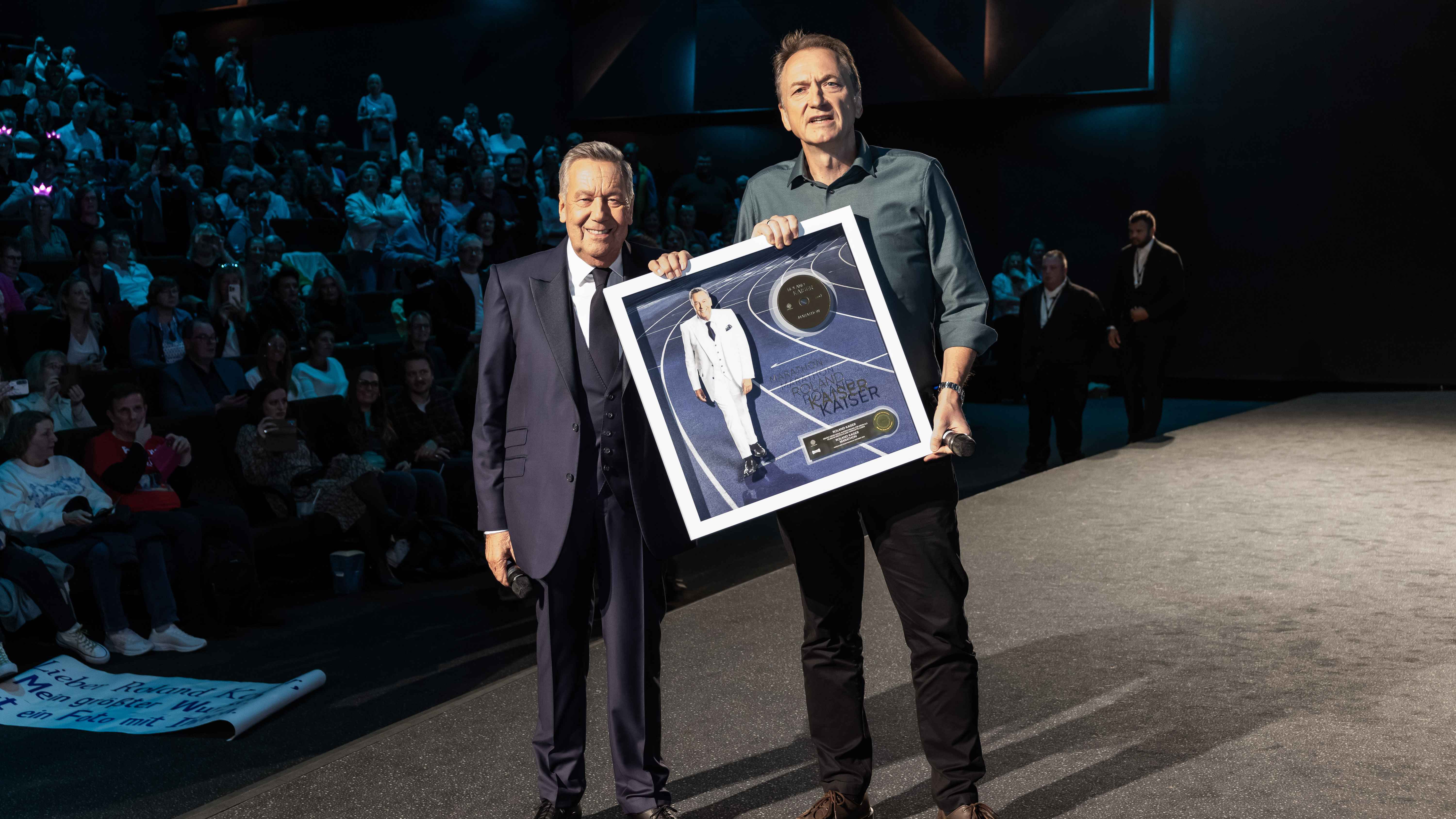 Feierten vor den Kinobesucher:innen Gold für "Marathon": Roland Kaiser (links) und Markus Hartmann (Senior Vice President Ariola Label Group Sony Music).