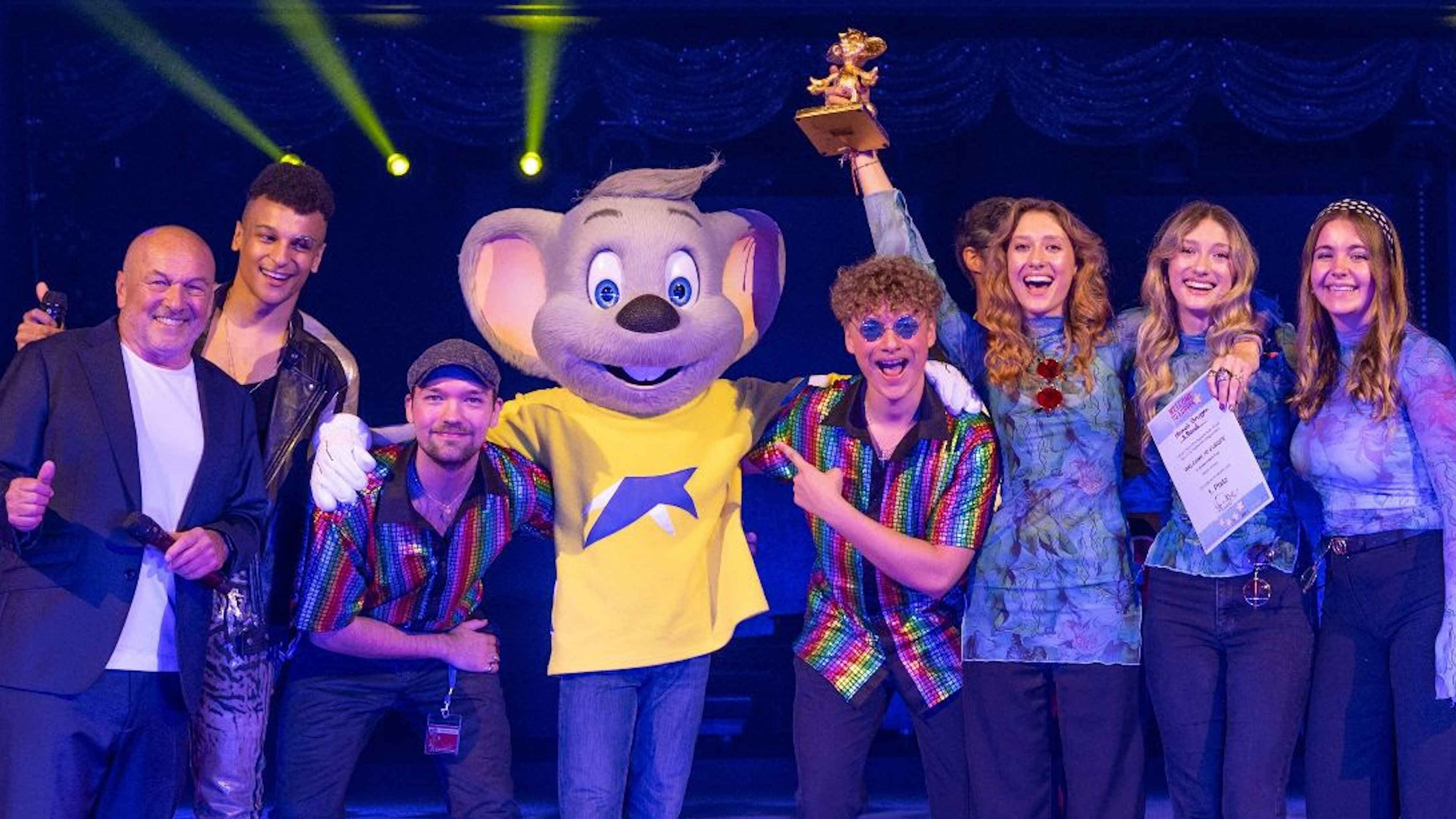 d2292c11 3958 41bf 8268 509469dce3bb Nach dem Wettbewerb (von links): Hans Derer (Contest-Leiter, CEO 7Us Media Group) sowie Moderator Prince Damien (Moderation) mit Hannah Brugger, ihrer Band und dem Europa-Park-Maskottchen Ed.
