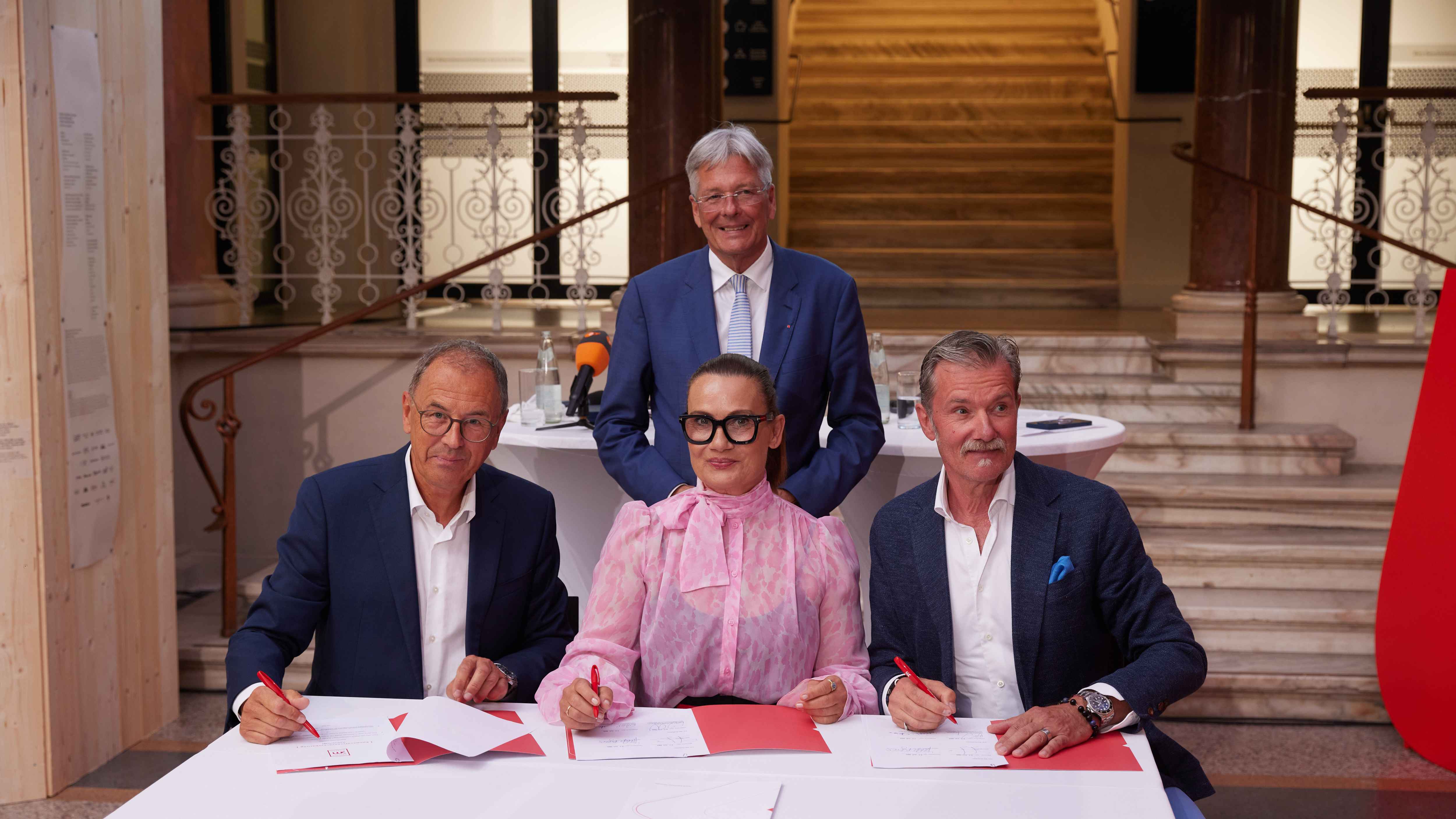 Bei der Unterzeichnung der Kooperatiionsvereinbarung (von links): Wolfgang Muchitsch (kärnten.museum Klagenfurt), Peter Kaiser (stehend, Landeshauptmann Kärnten), Jenny und John Jürgens.
