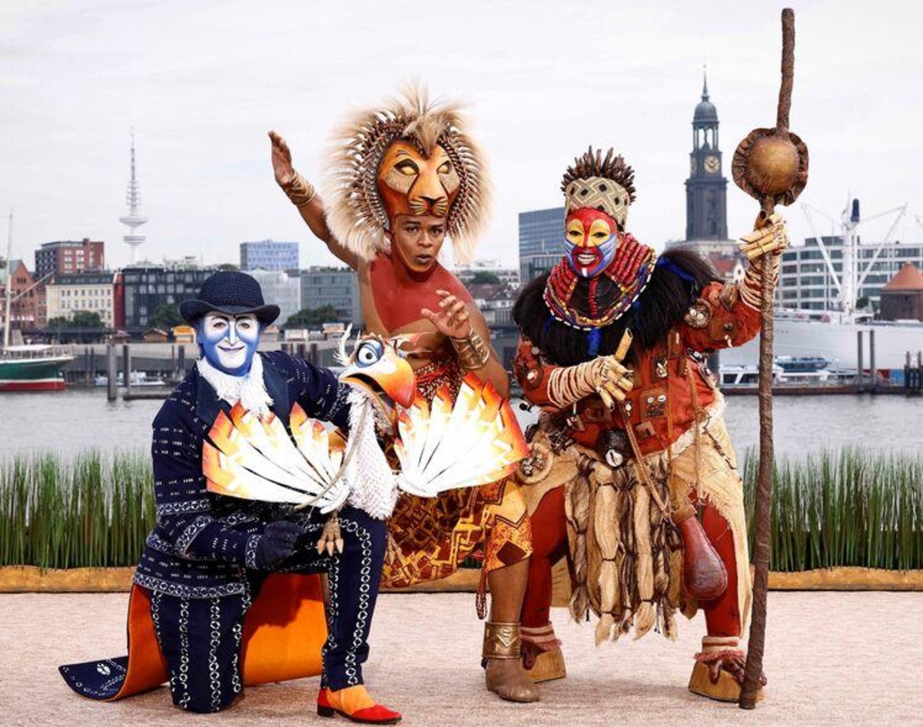 ea912ffd33f2d41ae4fe9b0a3636d1ea8ba12c045486c55a41410018d786b2da Wollen wieder auftreten: die Musical-Darsteller (von links) Simba (Hope Maine), Rafiki (Thenjiwe Nofemele) und Zazu (Joachim Benoit)