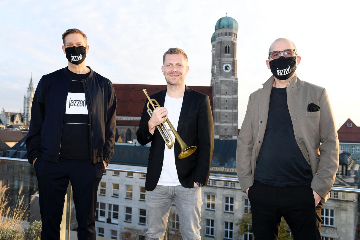ed894dacbf874a4686121e4853153e497446b8cc11a51eb1bcef0b49d966b44f Über den Dächern von München (von links): Götz Bühler (Chefredakteur jazzed), Nils Wülker und Marcel Engh (CMO jazzed)