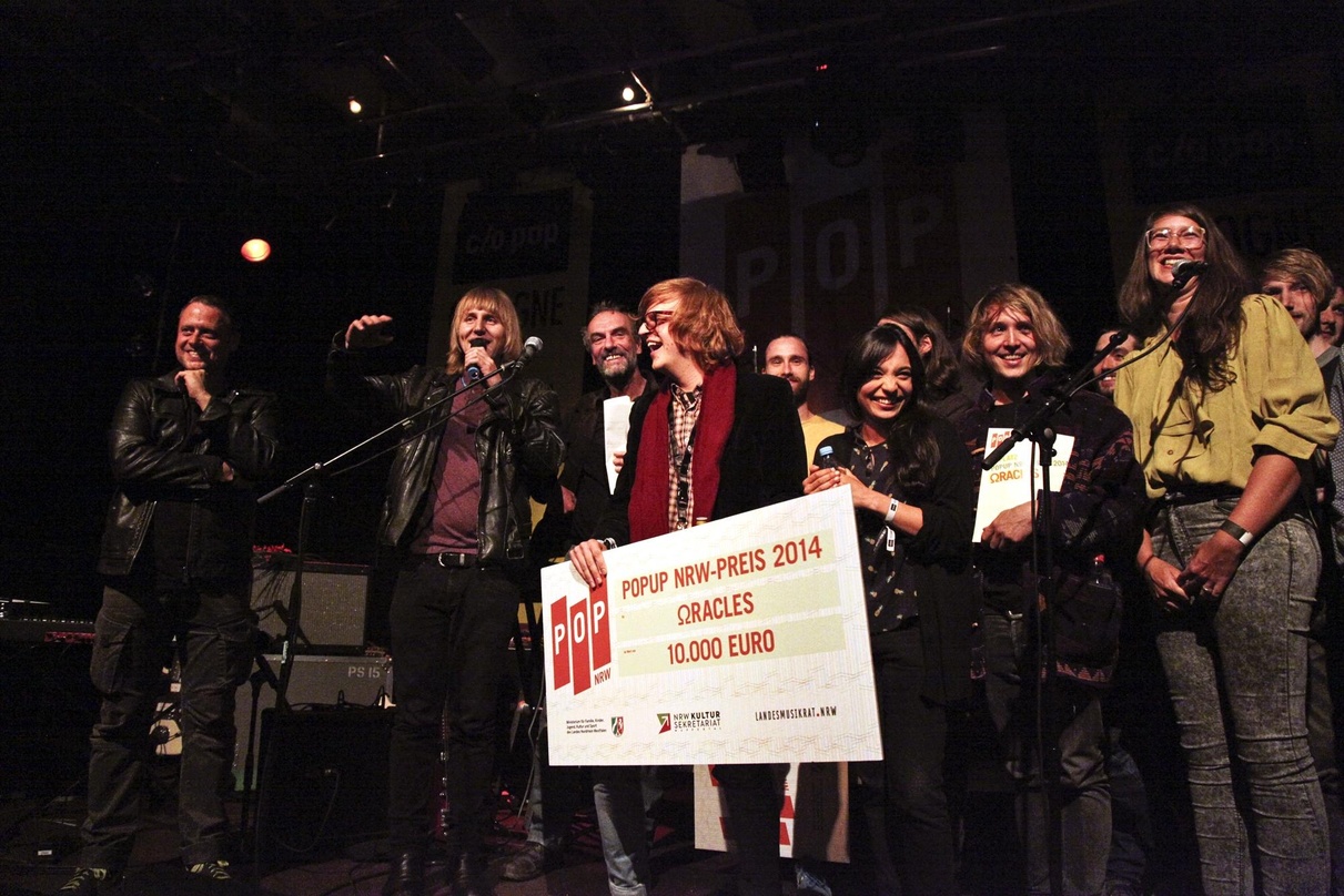 Ausgezeichnet: Die Gewinnerband Oracles mit Scheck und Jury von popUp NRW