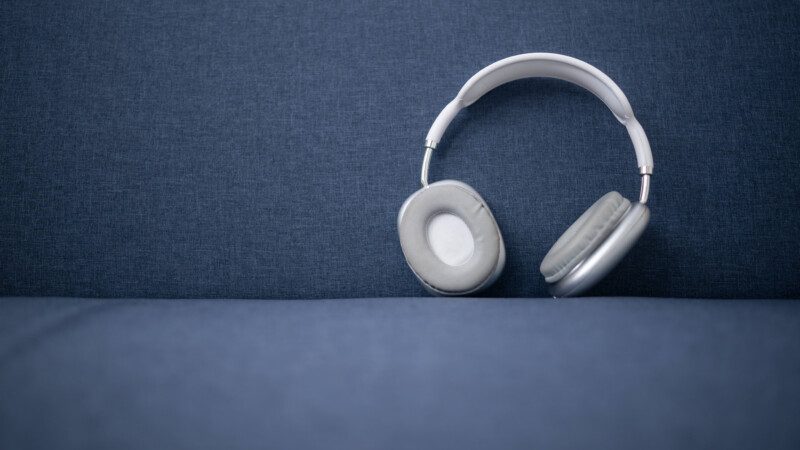 Weiße und graue kabellose Kopfhörer auf einem blauen Sofa, bereit, kraftvoll zu liefern
